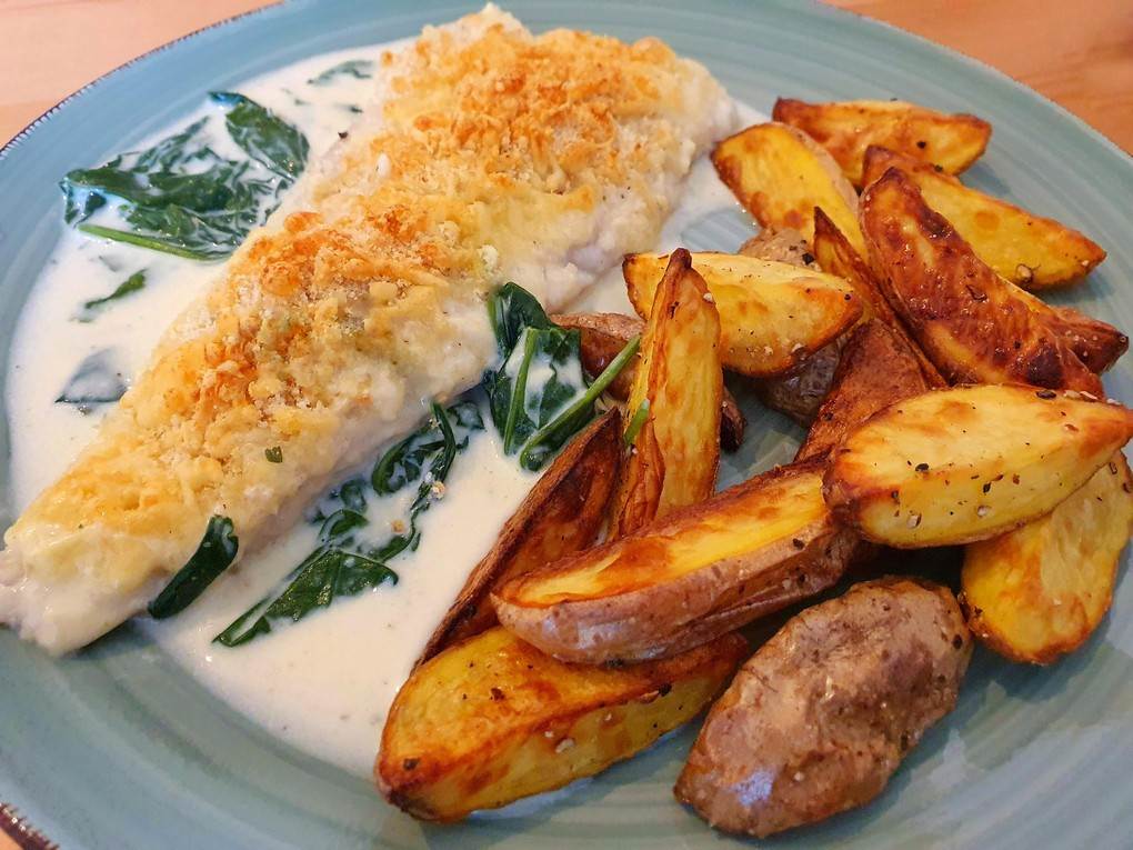 Seehecht auf Spinat-Sahne-Soße mit knusprigen Kartoffelspalten